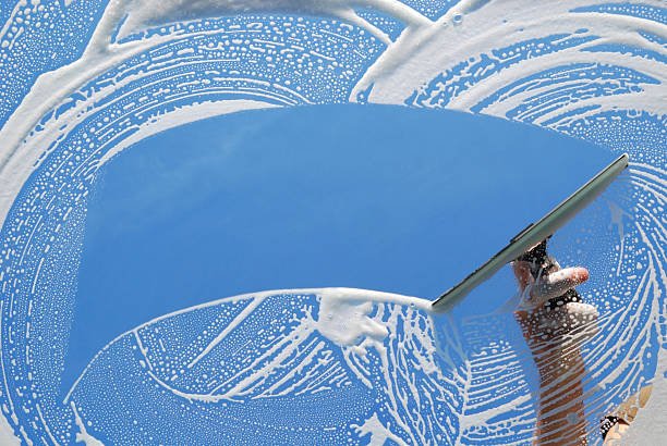 Accueil domestic window cleaner washing a window with a squeegee.